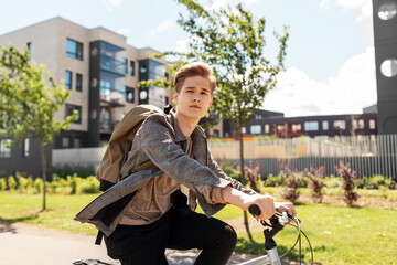 Wall Mural - lifestyle, transport and people concept - young man or teenage student boy with backpack riding bicycle on city street