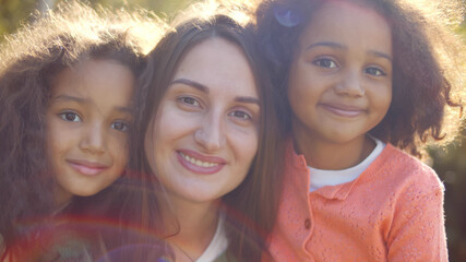 Wall Mural - Close up Portrait Of caucasian Mother And mixed race Daughters outdoors