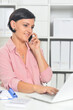 © aletia2011 - Young businesswoman talking on smartphone while working in office