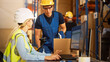 © Gorodenkoff - In Retail Warehouse Manager Uses Computer with Inventory Checking Software, Talks with Storehouse Worker about Package Delivery. International Distribution Center with Shelves Full of Products