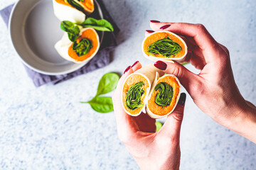 Canvas Print - Vegan tortilla wraps with sweet potato and spinach in hands, gray background, top view. Healthy vegetarian food concept.