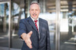 © Minerva Studio - Businessman giving an handshake in front of his office