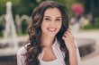 © deagreez - Photo portrait of beautiful young woman with curly hairstyle touching hair going in green city park wearing casual shirt