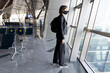 © epovdima - Young woman in a protective black mask with a backpack near window at the international airport terminal. Traveling during the coronavirus pandemic