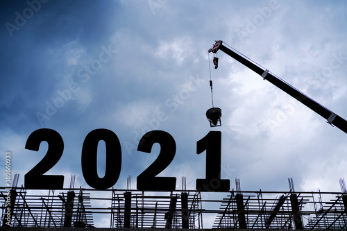 Fotografía Cranes building construction 2021year sign,Silhouette staff works as a team to p