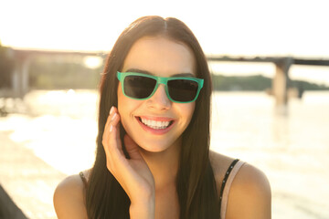 Sticker - Beautiful young woman wearing stylish sunglasses near river