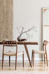 Stylish beige interior of dining room with design wooden oak table and chairs, vase with flowers, elegant rattan accessories and decoration. Korean style of home decor. Template.