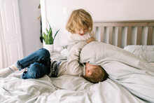 Two Siblings Playing On A Bed