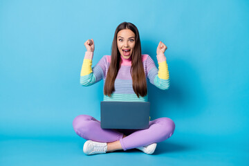 Wall Mural - Portrait of pretty glad cheerful girl sitting lotus position crossed legs using laptop having fun isolated over bright blue color background