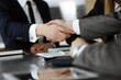 © Iryna - Unknown businessman shaking hands with his colleague or partner above the glass desk in modern office, close-up. Business people group at meeting