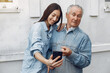 © prostooleh - Grandfather with granddaughter. Girl teaching her grandfather. Using a phone.