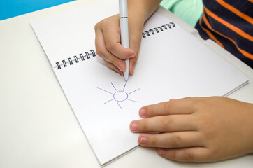 Wall Mural - child's hand draws the sun on a white notepad.