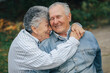 © prostooleh - Old couple in a park. Grandparents embracing. Woman in a blue shirt.