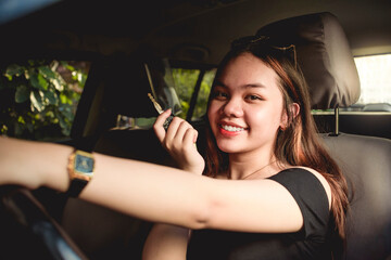 A young asian girl proudly shows the keys to her new car. Possible gift from parents or result of hardwork. Can represent a sale at a car dealership.