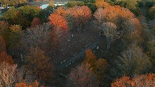 Aerial Shot Of A Cemetery Surrounded By Colorful Autumn Trees, Sunset