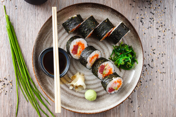 Sushi maki rolls with tuna, flying fish caviar, crab, avocado on a plate with chopsticks, soy sauce, wasabi and ginger. Japanese traditional food closeup served for lunch in modern gourmet restaurant