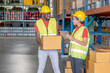 © narong - African American warehouse man and woman or factory worker work and discuss together about product box that man holding in workplace area. Concept of good management of staff working.