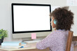 © insta_photos - African american elementary school kid girl wearing headphones virtual distance learning online looking at mock up white blank computer screen remote digital elearning at home. Over shoulder view