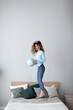 © BestForYou - Young happy woman jumping on the bed and tossing up the globe. Having fun at home.