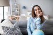 © BestForYou - Dreamy woman with a globe thinking a trip sitting on the couch at home.