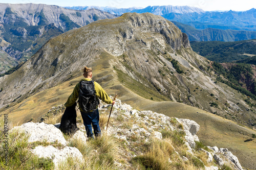 Fotografía un homme avec un sac à dos avec son chien , face à un panorama en montagne