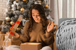© New Africa - Happy young woman opening Christmas gift at home. Magic holiday