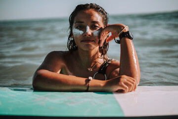 Wall Mural - Portrait of a young European female surfer with her hands on her surfboard