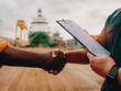 marine contractor businessman handshaking with worker on the ship with contract agreement. Handshake of two boilersuits with different colors wiyh maritime background