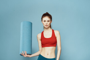 athletic woman with fitness mat exercise slim figure red t-shirt blue background