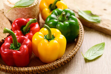 Fresh Yellow, Red And Green Bell Peppers In A Bamboo Basket On Wooden Background, Organic Vegetables