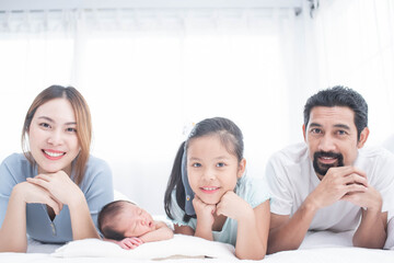 Wall Mural - happy family mother, father and children laughing, playing and smiling in bed in bedroom at home. a young family with young children to bed in the bedroom.