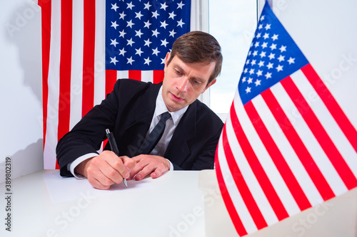 A man writes against the background of American flags. U.S. official. Employee of the American office. A businessman from the United States. American on the background of USA flags.