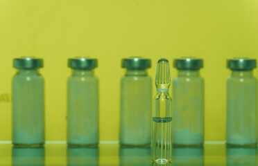 Glass medical ampoule vial for injection. Medicine is liquid sodium chloride with of aqueous solution in ampulla. Close up. Bottles ampule multicolor on background color and water. Human plasma.