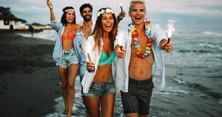 Wall Mural - friends having fun on the beach under sunset sunlight.