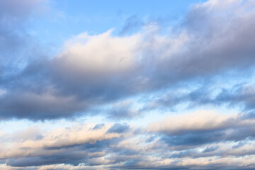 Wall Mural - low gray and white clouds in blue sky in autumn twilight