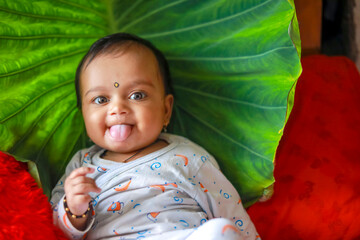 Canvas Print - Cute indian little child playing on bed with green leaf background