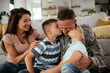 © JustLife - Happy soldier sitting on the floor with his family. Soldier and his wife enjoying at home with children