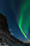 Fototapeta Kosmos - Spectacular dancing green strong northern lights over the famous round boulder beach near Uttakleiv on the Lofoten islands in Norway on clear winter night with snow-clad mountains