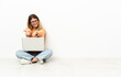 © luismolinero - Young woman with a laptop sitting on the floor holding copyspace imaginary on the palm to insert an ad