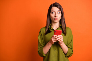 Wall Mural - photo of funny young girl hold telephone pout lips look empty space wear green shirt isolated orange