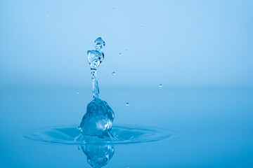 Wall Mural - Water drop splashing into blue water surface