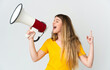 © luismolinero - Young blonde woman isolated on white background shouting through a megaphone to announce something in lateral position