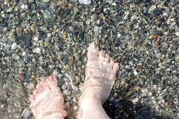 women's feet on the beach in sea water