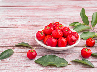 Ripe red cherries in a ceramic dish with leaves on a wooden table. Space for text. Sweet organic berries. Concept of healthy fruits