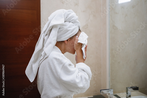 Fotomural Woman in a white robe and a towel on her head washes in the bathroom