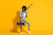 © deagreez - Full length photo of adorable lady wear casual denim outfit dancing boombox pointing empty space isolated yellow color background