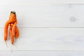 Ugly carrot on a wooden table. Ugly vegetables concept. Horizontal orientation, top view, copy space.