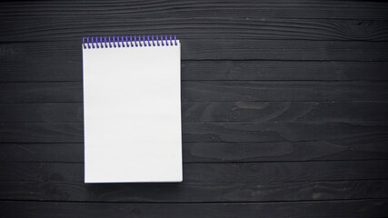 Blank paper notebook on brown wooden table background. Top view with copy space (selective focus). Office desk table concept