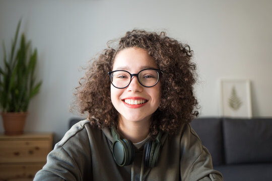 girl looks at camera and smiles. student talks over Internet. Video Conference or e-learning at home. portrait of teen at wide angle.