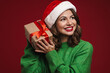 © Drobot Dean - Positive young woman in christmas santa hat holding present